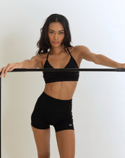 Front view of Fierce Model in a black clothes rack Wearing a black Color Ease Form Shorts while stretching. OJA Wear Philippines - Activewear & Athleisure for Pilates and Workouts
