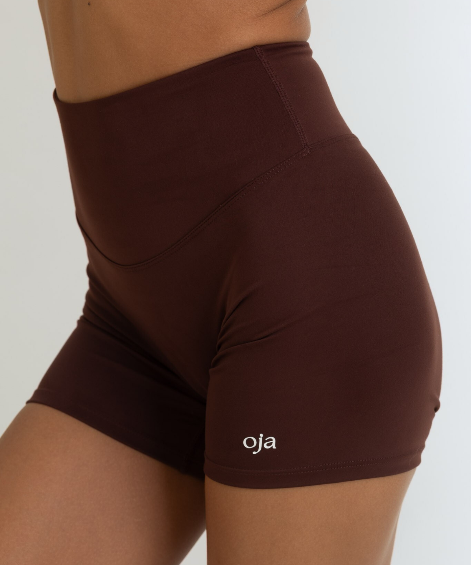Zoom view of Espresso Color Ease Form Shorts From with Silicone White Logo, OJA Wear Philippines - Activewear & Athleisure for Pilates and Workouts