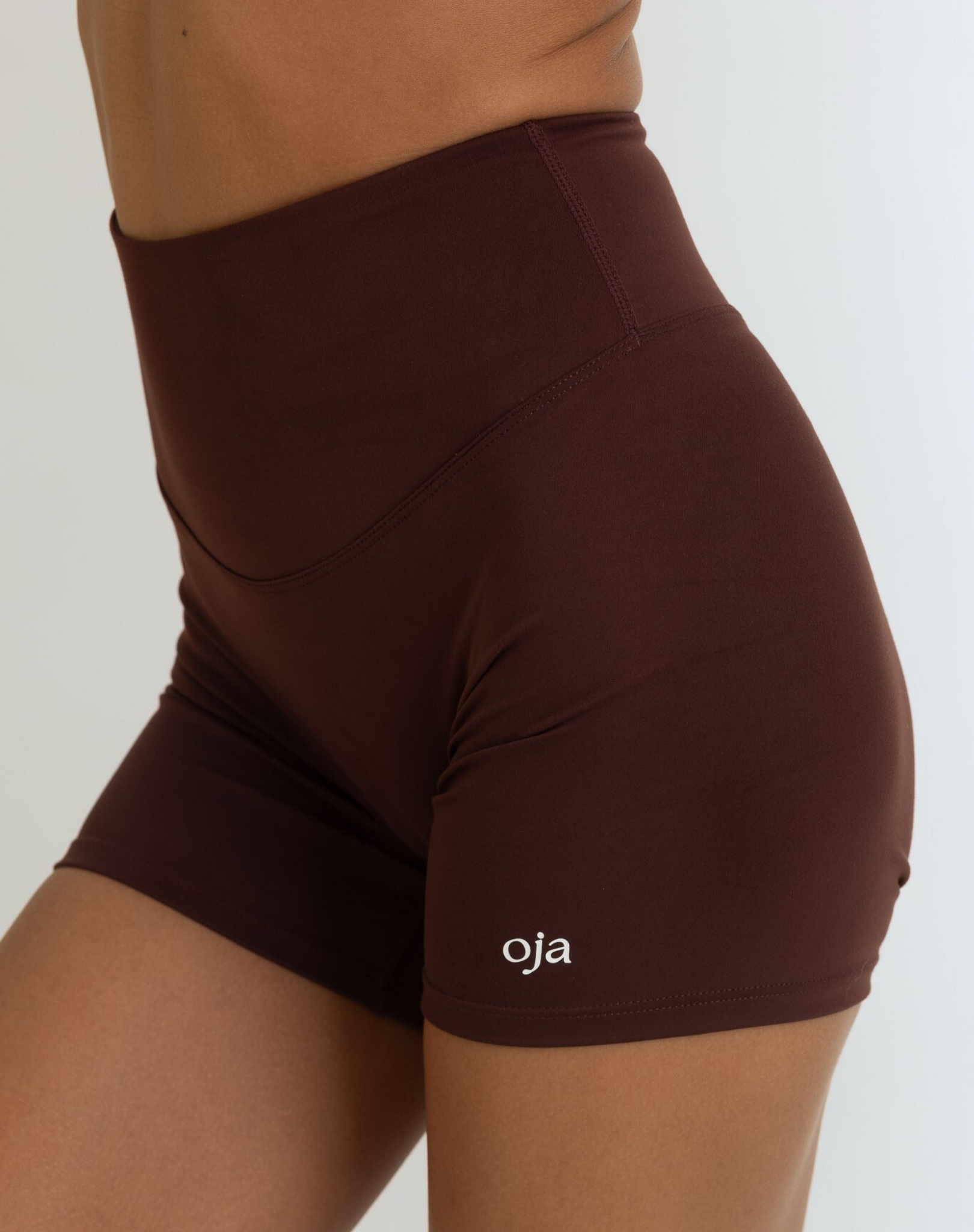 Zoom view of Espresso Color Ease Form Shorts From with Silicone White Logo, OJA Wear Philippines - Activewear & Athleisure for Pilates and Workouts